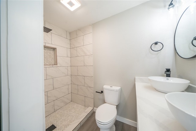 bathroom with a tile shower, vanity, and toilet