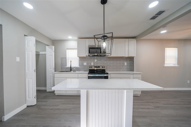 kitchen with sink, decorative light fixtures, a kitchen island, white cabinetry, and stainless steel appliances