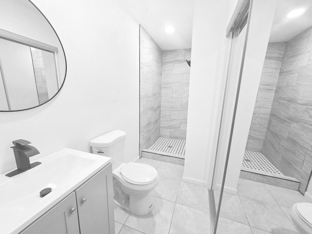 bathroom featuring a tile shower, vanity, and toilet