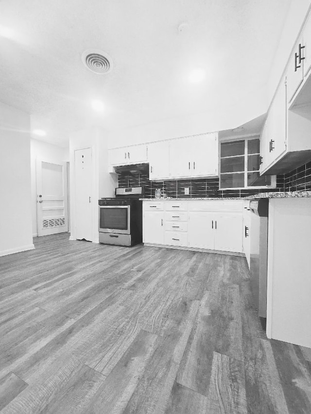 kitchen featuring white cabinets, decorative backsplash, stainless steel appliances, and hardwood / wood-style flooring