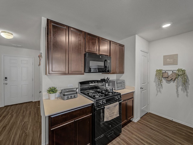 kitchen featuring dark brown cabinetry, dark wood-type flooring, and black appliances