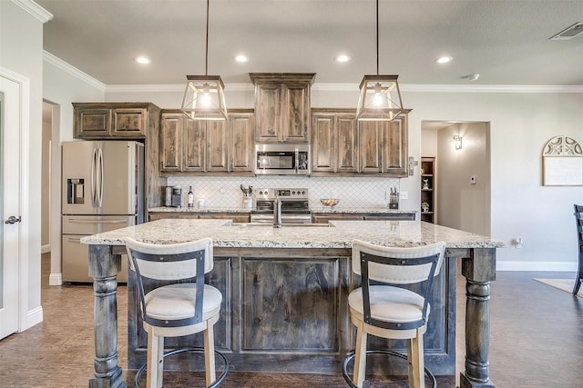 kitchen with sink, a kitchen island with sink, a kitchen bar, decorative backsplash, and appliances with stainless steel finishes