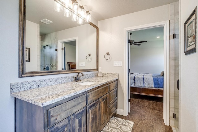 bathroom featuring hardwood / wood-style floors, vanity, a shower with door, ceiling fan, and a textured ceiling