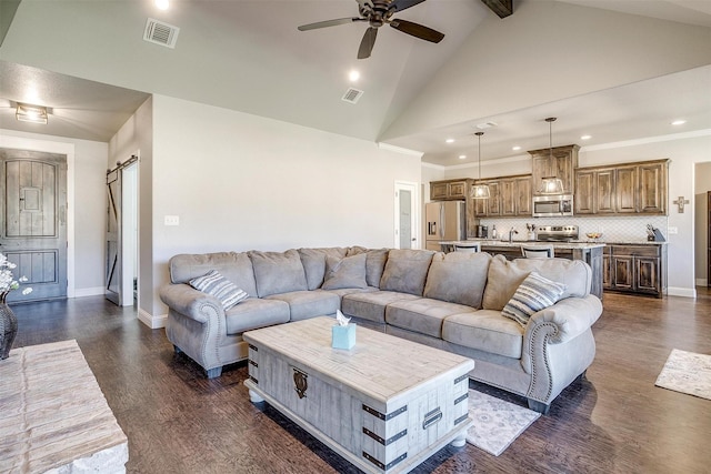 living room with ceiling fan, a barn door, beamed ceiling, high vaulted ceiling, and dark hardwood / wood-style floors