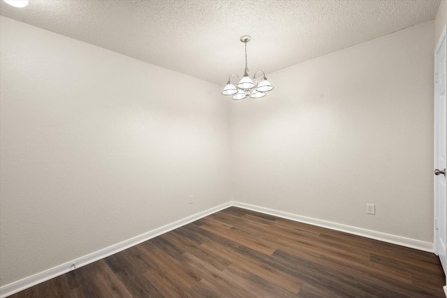 unfurnished room featuring dark wood-type flooring, a textured ceiling, and an inviting chandelier