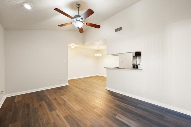 unfurnished living room with ceiling fan with notable chandelier, a textured ceiling, vaulted ceiling, and dark wood-type flooring