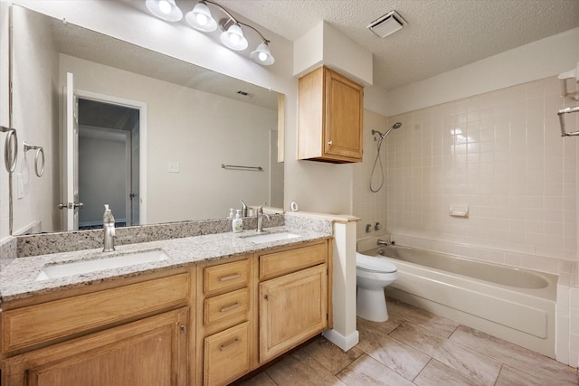 full bathroom featuring vanity, a textured ceiling, toilet, and tiled shower / bath combo