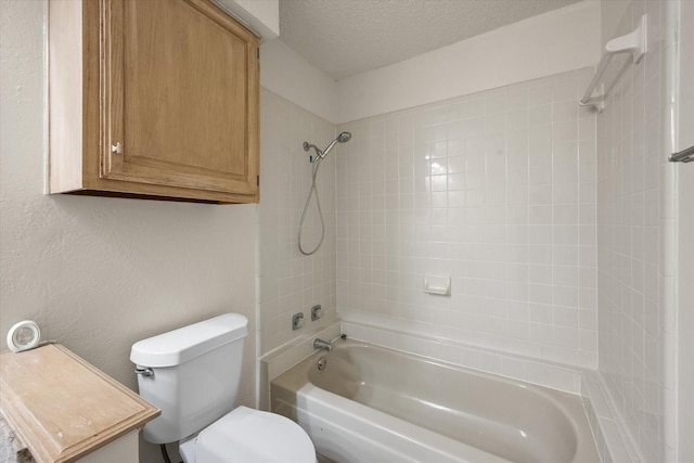 bathroom featuring a textured ceiling, toilet, and tiled shower / bath