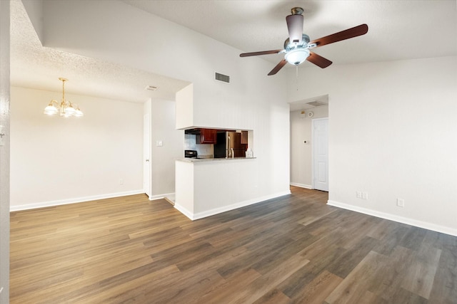 unfurnished living room featuring ceiling fan with notable chandelier, a textured ceiling, dark hardwood / wood-style flooring, and high vaulted ceiling