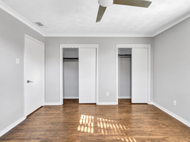 unfurnished bedroom featuring two closets, ceiling fan, ornamental molding, and dark hardwood / wood-style floors