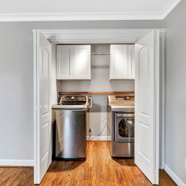 washroom featuring cabinets, separate washer and dryer, crown molding, and light hardwood / wood-style flooring