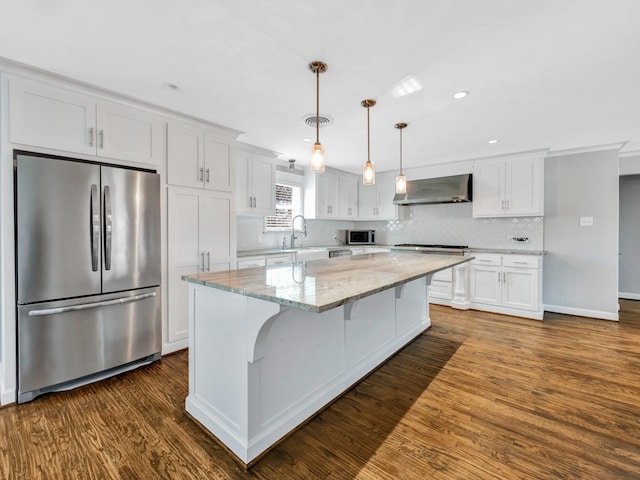 kitchen featuring white cabinets, a center island, wall chimney range hood, and stainless steel appliances