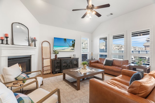 living room with ceiling fan, plenty of natural light, vaulted ceiling, and light wood-type flooring