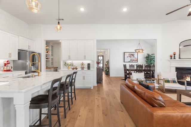 kitchen with white cabinets, decorative light fixtures, light hardwood / wood-style floors, and stainless steel fridge with ice dispenser