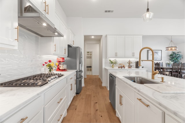 kitchen featuring backsplash, stainless steel appliances, sink, white cabinets, and hanging light fixtures