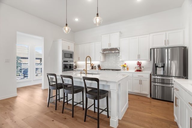 kitchen featuring stainless steel appliances, white cabinetry, and a center island with sink