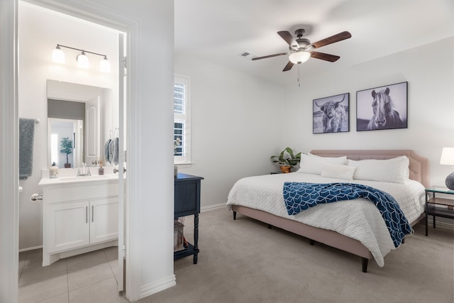 bedroom with ensuite bath, ceiling fan, sink, and light colored carpet