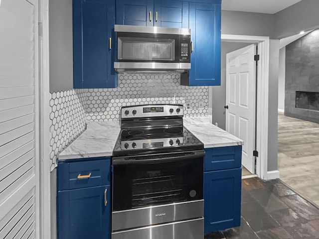 kitchen with a tile fireplace, blue cabinetry, backsplash, and appliances with stainless steel finishes