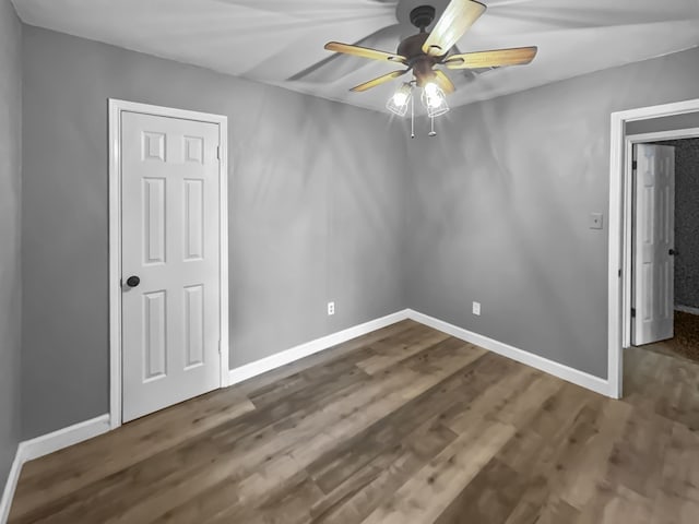 empty room with dark hardwood / wood-style flooring and ceiling fan