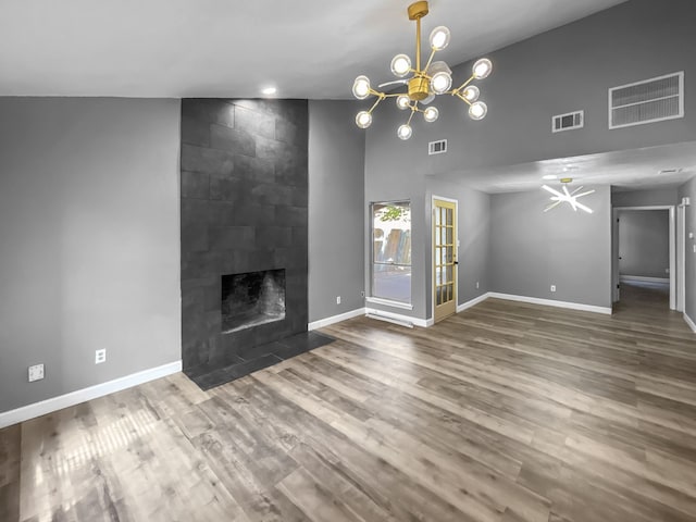 unfurnished living room with a fireplace, vaulted ceiling, a notable chandelier, and dark hardwood / wood-style floors