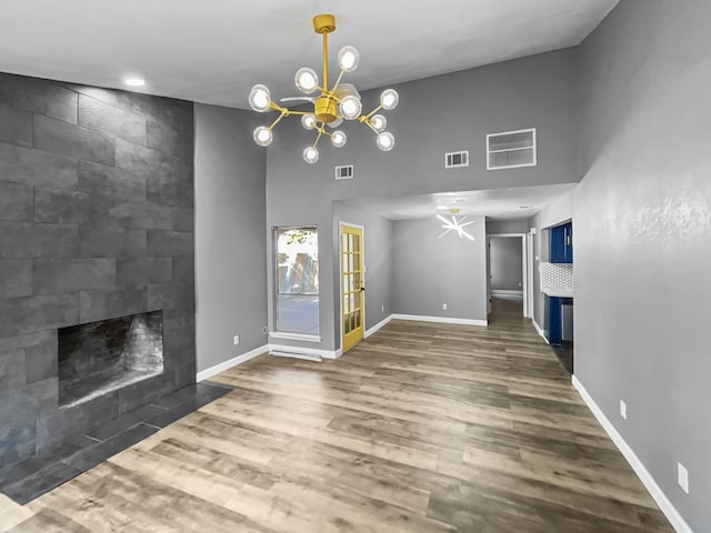 unfurnished living room featuring dark hardwood / wood-style flooring, a tile fireplace, and a chandelier