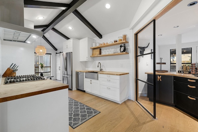 kitchen featuring vaulted ceiling with beams, white cabinetry, hanging light fixtures, appliances with stainless steel finishes, and wood counters