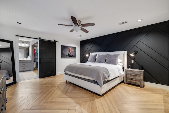 bedroom with ceiling fan, light parquet floors, and a barn door