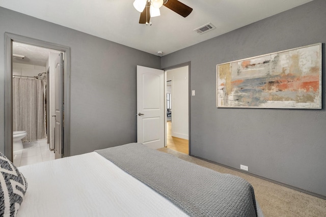 bedroom with ceiling fan, light carpet, and ensuite bathroom