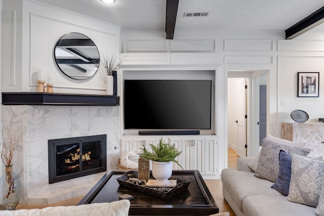 living room with a textured ceiling, a high end fireplace, and beam ceiling