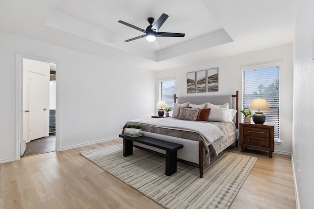 bedroom featuring light wood-type flooring, a tray ceiling, and ceiling fan