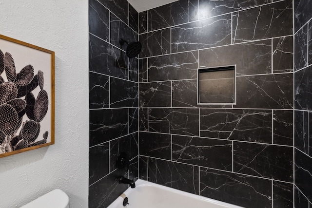 bathroom with toilet and tiled shower / bath