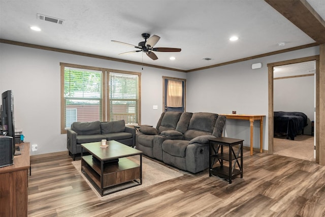 living room featuring hardwood / wood-style floors, ceiling fan, and crown molding