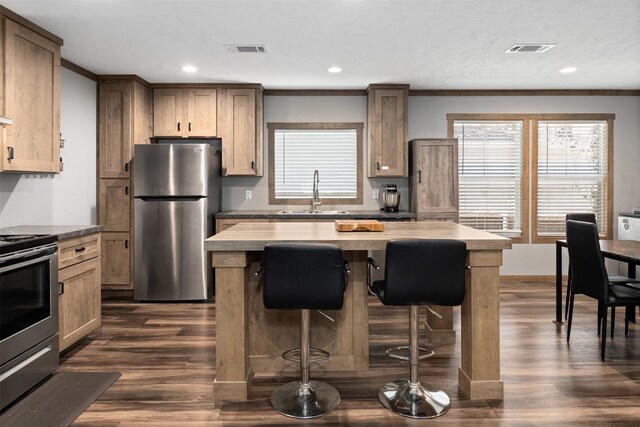 kitchen featuring appliances with stainless steel finishes, sink, a breakfast bar area, a center island, and butcher block counters