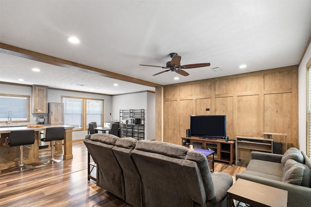 living room with ceiling fan, sink, beamed ceiling, and hardwood / wood-style flooring