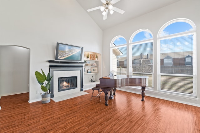 miscellaneous room with high vaulted ceiling, ceiling fan, hardwood / wood-style flooring, and a tile fireplace