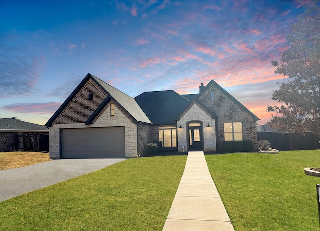 french country inspired facade featuring concrete driveway, stone siding, fence, a front lawn, and brick siding