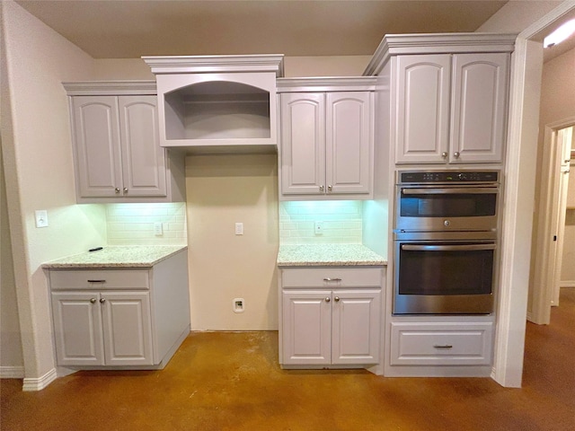 kitchen with white cabinetry, decorative backsplash, light stone countertops, and stainless steel double oven