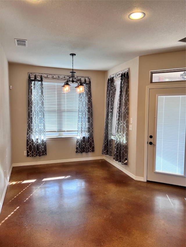 unfurnished dining area featuring a textured ceiling and a chandelier