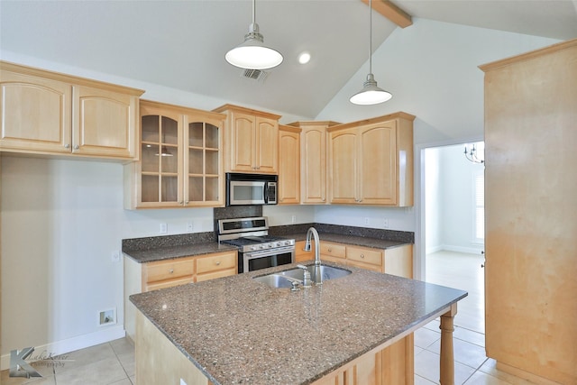 kitchen featuring stainless steel appliances, sink, light brown cabinets, beam ceiling, and an island with sink