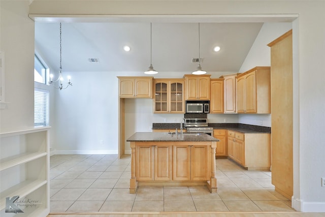 kitchen with lofted ceiling, a center island with sink, light tile patterned floors, decorative light fixtures, and stainless steel appliances