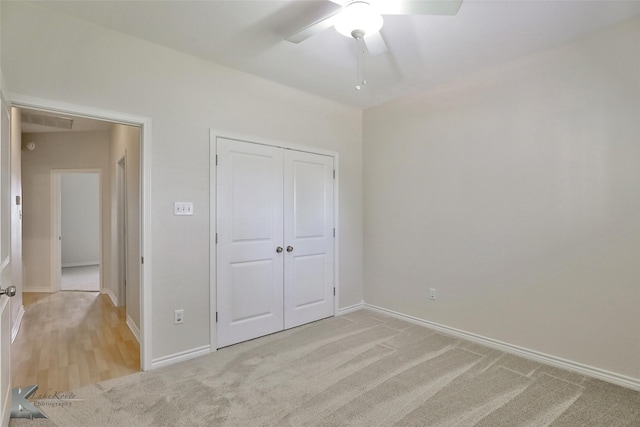 unfurnished bedroom featuring ceiling fan, a closet, and light carpet