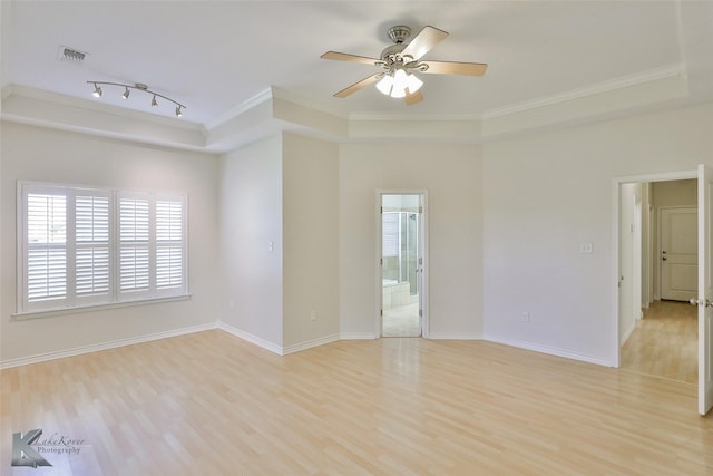 empty room featuring a tray ceiling, ornamental molding, and light hardwood / wood-style floors