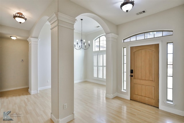 foyer featuring an inviting chandelier, light hardwood / wood-style floors, and decorative columns