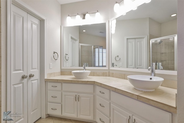 bathroom with tile patterned floors, a shower with door, and vanity