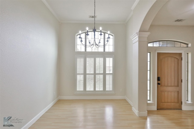 entryway featuring decorative columns, ornamental molding, a chandelier, and light wood-type flooring