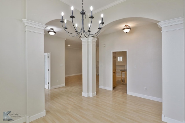 unfurnished dining area with decorative columns, a chandelier, light hardwood / wood-style floors, and ornamental molding