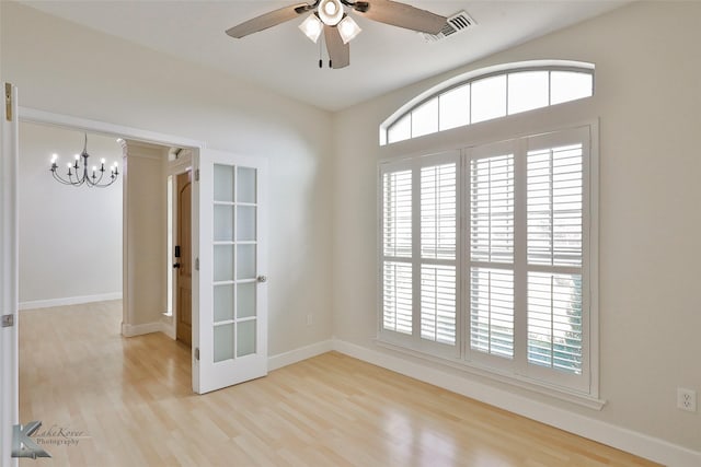 unfurnished room with plenty of natural light, light wood-type flooring, and ceiling fan with notable chandelier