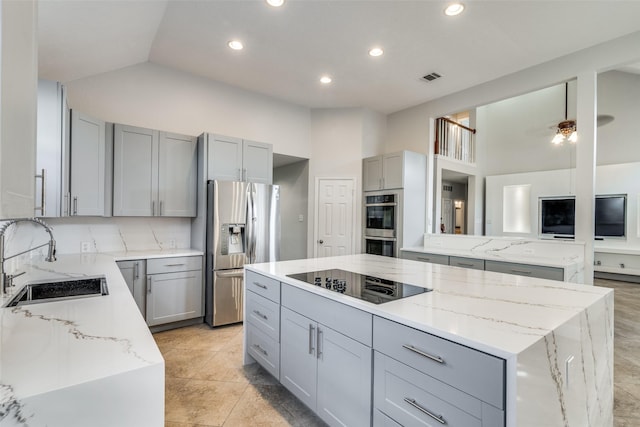 kitchen featuring gray cabinetry, sink, light stone countertops, a kitchen island, and stainless steel appliances