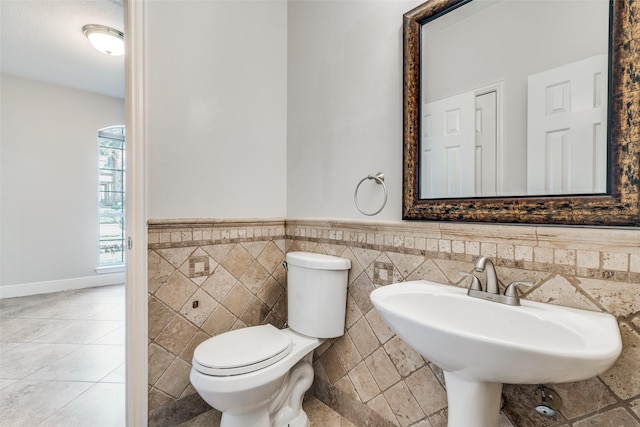 bathroom with toilet, tile walls, and sink