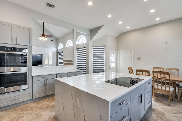 kitchen with gray cabinetry, a center island, lofted ceiling, black electric stovetop, and double oven